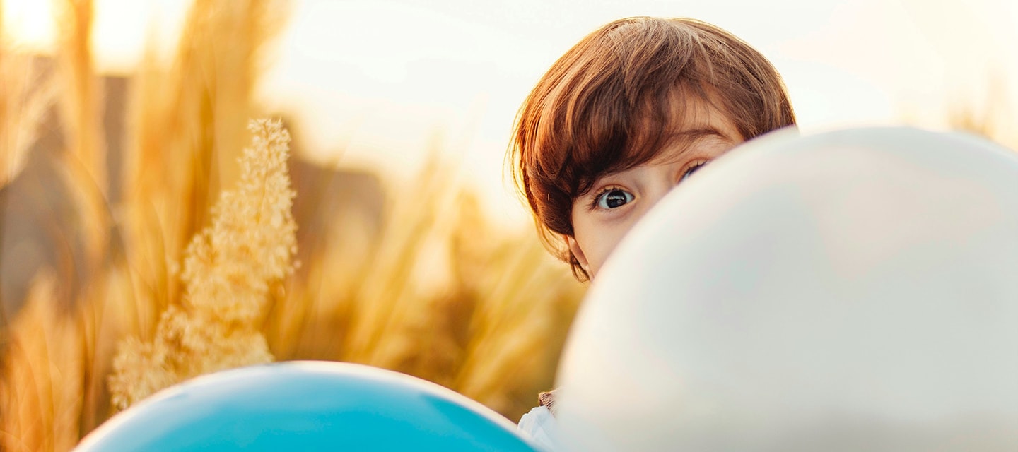 Child peaking out behind balloons